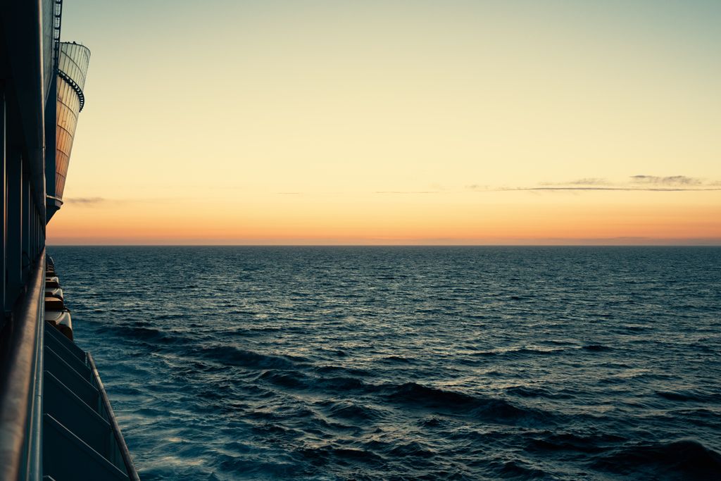 Beautiful ocean view from a cruise ship deck during sunset, capturing the serene waves and colorful sky.